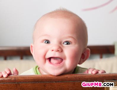 A very happy baby hanging out in his crib.